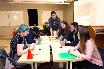 一群商业学生围坐在一张桌子在一个项目中工作